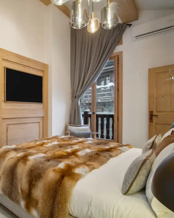 Chambre du chalet avec lit douillet et balcon ouvert sur la neige