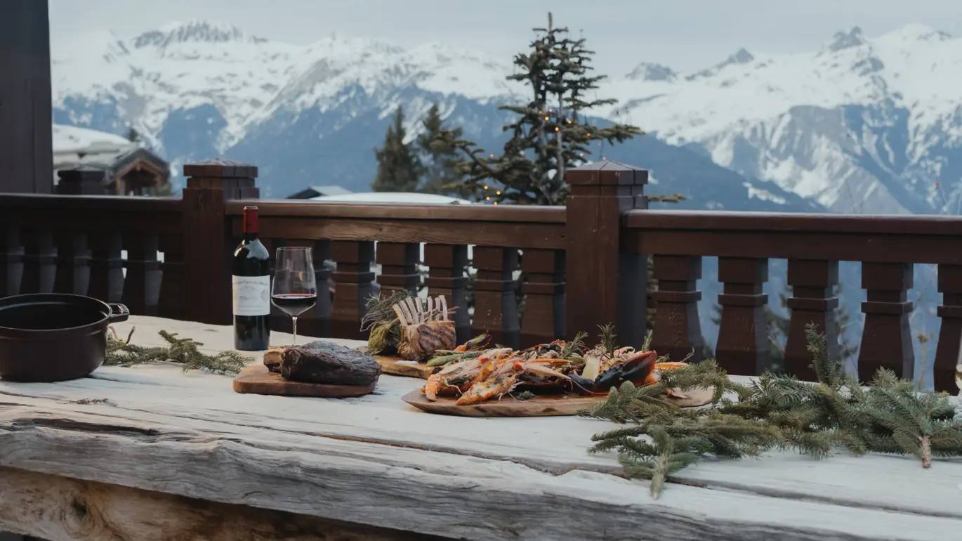 Repas sur la terrasse du chalet face aux montagnes enneigées