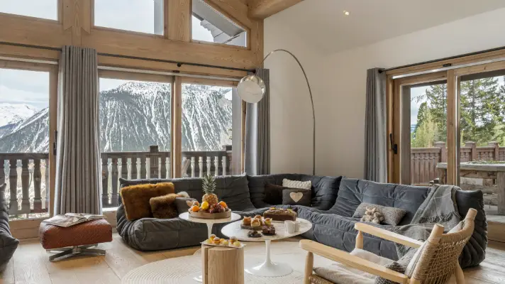 Salon lumineux ouvert sur les montagnes par de grandes baies vitrées