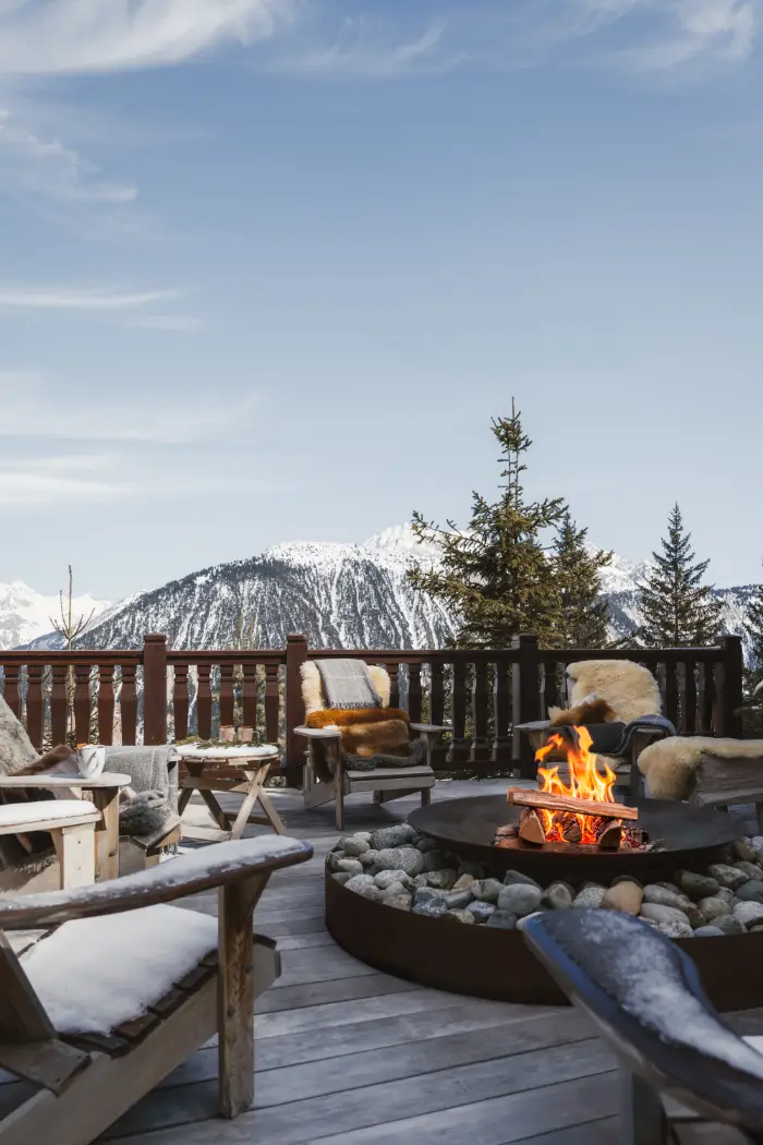 Terrasse du chalet avec brasero et fauteuils face aux montagnes